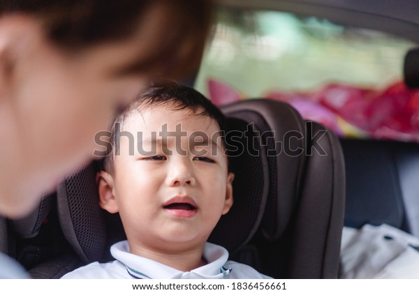 Asian stubborn child baby boy while mother scolding\
on car seat in the car when he go back to school in the\
morning.Little asian toddler boy in booster seat make crying\
face.Transportation safe\
trip.