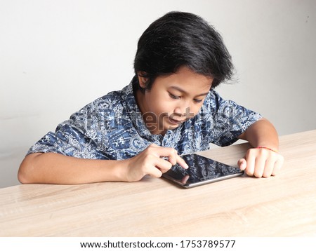 Asian student boy learning online and taking exam using tablet. Stay at home and social distancing during corona pandemic. 