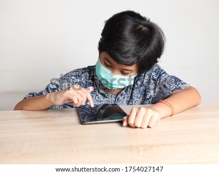 Asian student boy learning online and taking exam using tablet. Stay at home and social distancing during corona pandemic. 