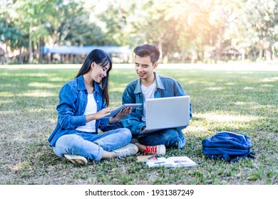 Asian Student Couple Studying Outside On The Grass, Sitting Down On The School Campus Using Laptop Computer, Books, Pencil And Note Book, Studying Hard Under The Trees Nature In The Evening Sunlight