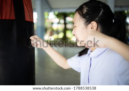 Asian student girl is crying and raising fists,female people is punching into punch bag takes out her anger,emotional explosion,stress relief,feels angry,disappointed,self- loathing,catharsis concept