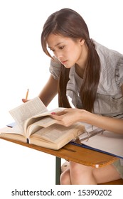 Asian Student Girl Sitting By The Desk And Studying English Dictionary In Preparation For Test, Exam Or Spelling Bee Contest