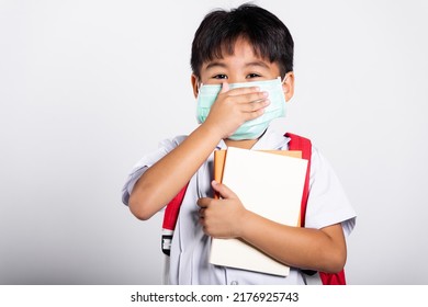 Asian Student Kid Boy Wearing Student Thai Uniform And Medical Protect Face Mask And Hand Cover Mouth In Studio Shot Isolated On White Background, New Normal Back To School