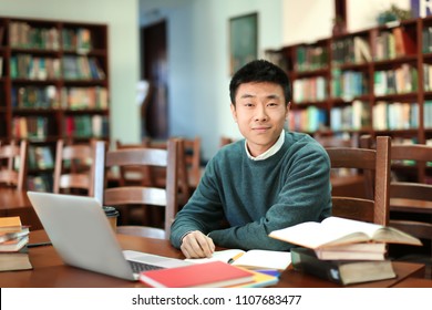 Asian Student With Laptop Studying In Library