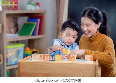 Asian Student In Preschool Use A Letter Box Make A Study Word In Class Room With His Teacher, This Image Can Use For Genius, Clever, Education And School Concept.