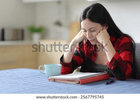 Asian student studying memorizing notes in the kitchen at home