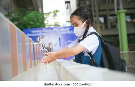 Asian student  washing hands at the outdoor wash basin in the school. Preventing Contagious diseases, Plague. Kids health, protecting the virus Covid - 19 , Saving water, Cleaning, Running water.