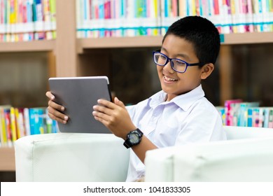 Asian student is watching movie on tablet in the library with happiness. - Powered by Shutterstock