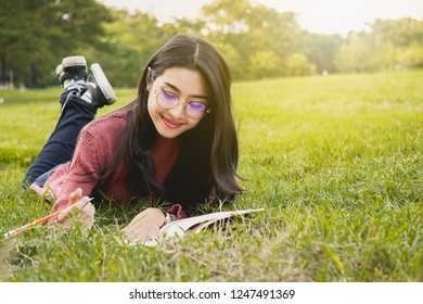 Asian student woman reading in park for education concept