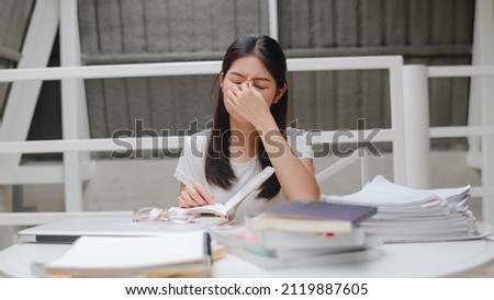 Asian student women read books in library at university. Young undergraduate girl stress tired have problem while study hard for knowledge on lecture desk at college campus concept.