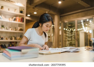 Asian student women reading books in library at university. Young undergraduate girl do homework, read textbook, study hard for knowledge on lecture desk at college campus overtime night. - Shutterstock ID 2037759395