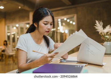 Asian Student Women Reading Books In Library At University. Young Undergraduate Girl Do Homework, Read Textbook, Study Hard For Knowledge On Lecture Desk At College Campus Overtime Night.