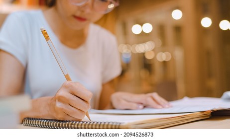 Asian Student Women Reading Books In Library At University. Young Undergraduate Girl Do Homework, Read Textbook, Study Hard For Knowledge On Lecture Desk At College Campus Overtime Night.