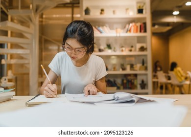 Asian Student Women Reading Books In Library At University. Young Undergraduate Girl Do Homework, Read Textbook, Study Hard For Knowledge On Lecture Desk At College Campus Overtime Night.