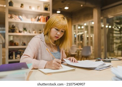 Asian Student Women Reading Books In Library At University. Young Undergraduate Girl Do Homework, Read Textbook, Study Hard For Knowledge On Lecture Desk At College Campus Overtime Night.