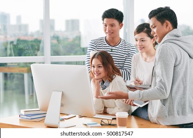 Asian Students Gathered At Computer To Discuss Project