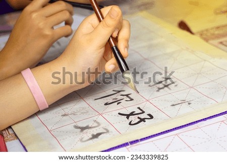 Asian students practice the art of Chinese calligraphy by writing Chinese characters, the word 