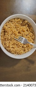 Asian Style Noodle With Soy Sauce And Beef Sauce Packet Seasoning Closeup With Stainless Steel Fork In White Glass Bowl