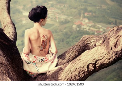 Asian style portrait young woman sitting the tree branch and snake tattoo her back (original)