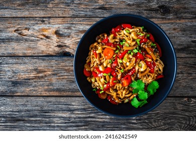 Asian style stir fried vegetables and noodles on wooden table 