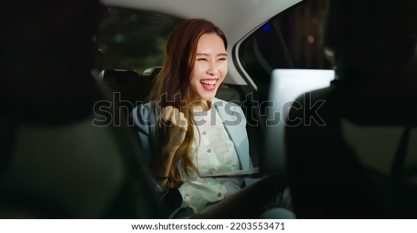 asian successful business\
woman use laptop computer to work and she gets orders in the car at\
night