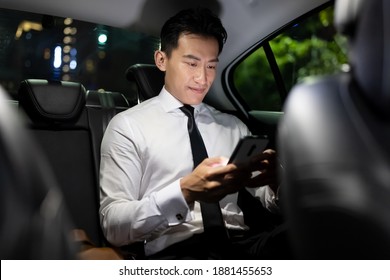asian successful businessman use smart phone in the taxi at night