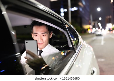 Asian Successful Businessman Use Smart Phone In The Car At Night