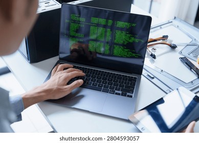 Asian IT support engineer holding tablet and typing on laptop AI vibe coding.