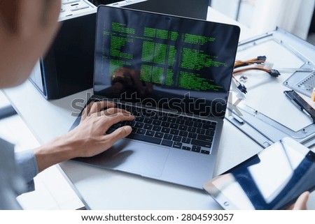Asian IT support engineer holding tablet and typing on laptop AI vibe coding.
