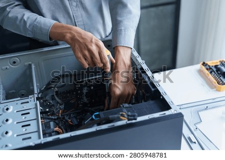 Asian IT support engineer using screwdriver fixing broken part in pc.