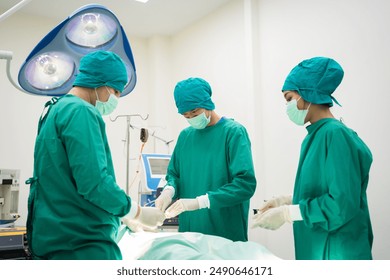 Asian surgeons team in green scrubs and masks discussing procedure in operating room. Medical professionals preparing for surgery, showcasing focus, communication, and teamwork in sterile environment. - Powered by Shutterstock