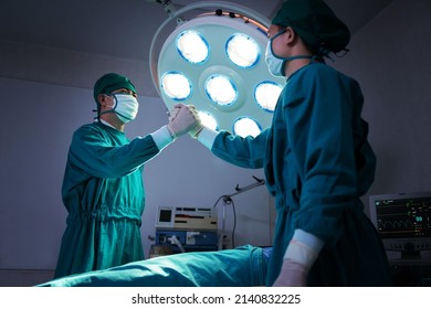 Asian Surgical Team Having Handshake After Success Surgery In The Hospital Operating Room