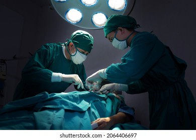 Asian Surgical Team Performing Surgery In The Hospital Operating Room