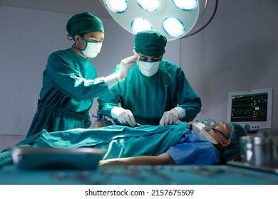 Asian Surgical Team Performing Surgery In The Hospital Operating Room