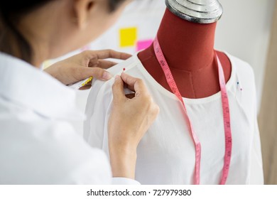 Asian tailor adjusts garment design on mannequin in workshop make a little adjustment to her work on model in the studio - Powered by Shutterstock