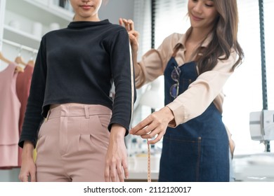 Asian tailor woman measure customer's body to making her new clothes. Attractive female fashion designer dressmaker working and design new fashion collection for customer in tailoring atelier workshop - Powered by Shutterstock