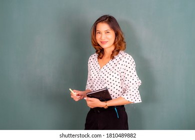 Asian Teacher At The Board With Books In Preschool For Disability Children.  Professional Woman Copy Space On Background Concept. 