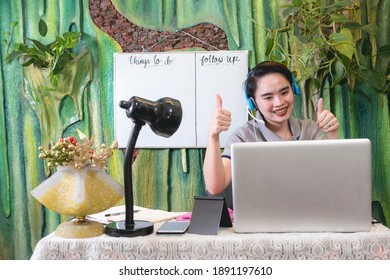 An Asian Teacher Gives A Double Thumbs Up To Her Online Students. Concept Of Passing A Student Or Giving Approval.Work At Home Setup.