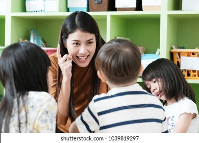 Asian teacher in kindergarten classroom, Preschool asia kids read book with teacher at school, Asian woman teaching english for children in classroom, Preschool, kindergarten education concept