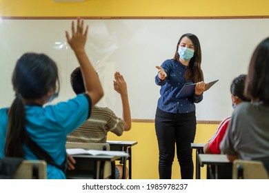 Asian Teacher And Student Having A Lesson With Face Mask Back At School After Covid-19 Quarantine And Lockdown.