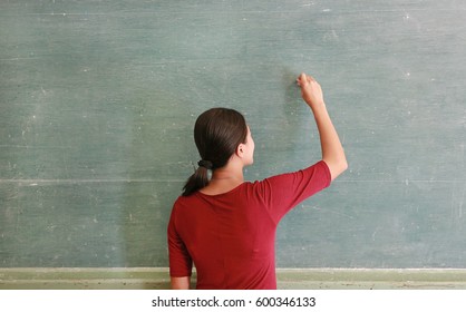 Asian Teacher Writing On Blackboard With Chalk In Classroom, Educations Concept.