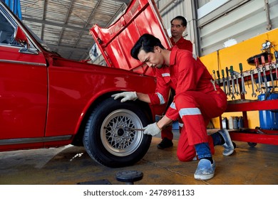 Asian technician male try to repair or swap a car wheel in car garage with senior technician team to help. - Powered by Shutterstock