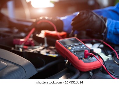 Asian Technician Measure Voltage Of Battery In The Car At Service Station, Maintenance And Repair