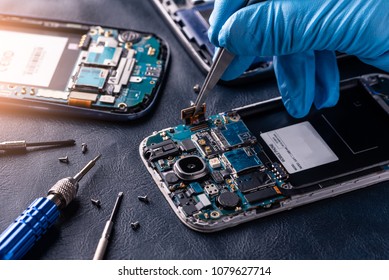 The asian technician repairing the smartphone's motherboard in the lab with copy space. the concept of computer hardware, mobile phone, electronic, repairing, upgrade and technology.