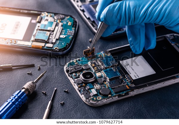 The asian\
technician repairing the smartphone\'s motherboard in the lab with\
copy space. the concept of computer hardware, mobile phone,\
electronic, repairing, upgrade and\
technology.