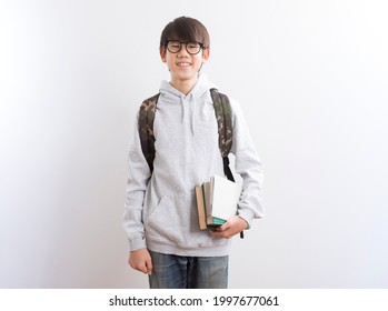 Asian Teen Boy Students Carrying A Backpack And Books Standing On White Background.