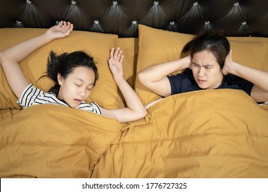 Asian Teen Daughter Snoring With Open Mouth,mother Is Closing Ears With Hands,loud Noise,annoying Snoring Of Child Girl,risk Of Sleep Apnea While Sleeping,unhappy Woman Wakes Up While Lying In The Bed