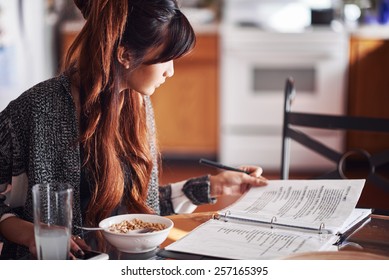 asian teen doing homework on kitchen table