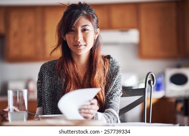 Asian Teen Girl With Homework In Kitchen