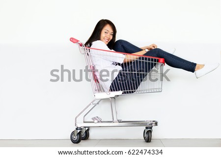 asian teen girl in shopping cart with hat in fashion shopaholic concept